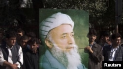 Supporters of Burhanuddin Rabbani, former Afghan president and head of the government's peace council, hold a picture of him as they stand outside his house a day after he was killed in Kabul on September 21.