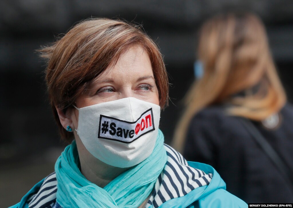 Një protestuese ukrainase në Kiev mban maskë mbrojtëse me mbishkrimin "shpëto biznesin e vogël".