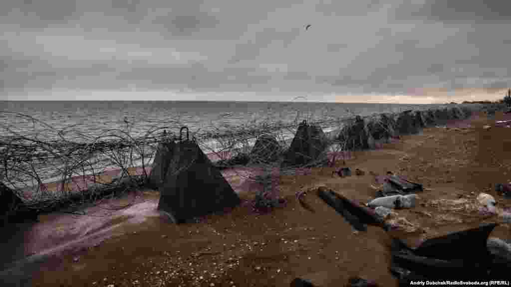 The beach of Shyrokyne, with razor wire strung between &ldquo;dragon&rsquo;s teeth&rdquo; (concrete pyramids designed to stop a military beach landing). Off the beach, naval mines lurk under the waves.