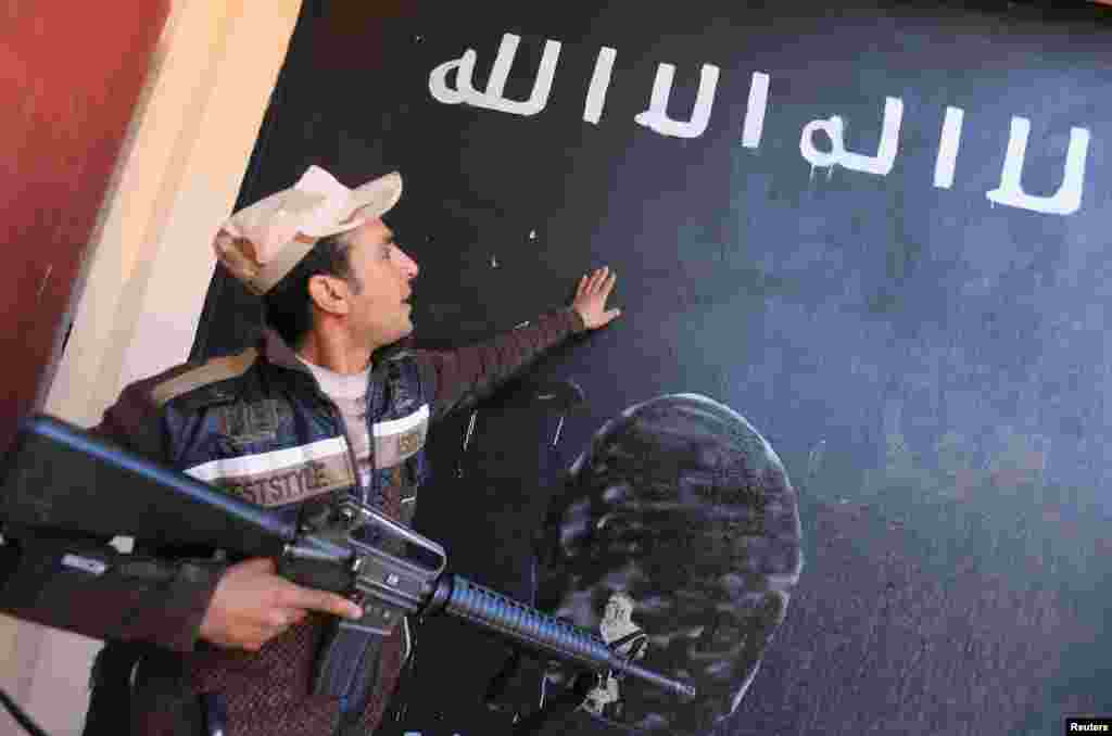 An Iraqi soldier looks at a wall painted in the colors of the black flag commonly used by Islamic State militants, in the village of Argub, Iraq. (Reuters/Ari Jalal)