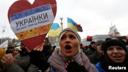 A woman holds a sign saying "Ukranian ladies are waiting for you on Maidan" as she takes part in a pro-EU integration rally in Independence Square.