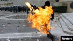 Демонстрант фрла молотов коктел кон полицијата пред грчкиот парламент на денешните протести во Атина.