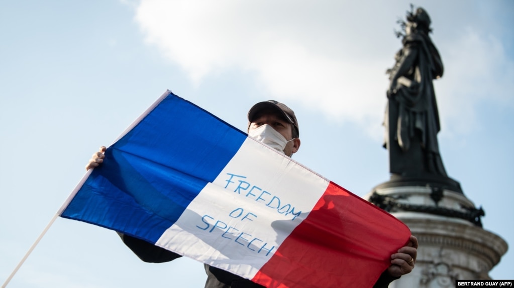 Un bărbat cu steagul francez în timpul unei demonstrații în Place de la Republique din Paris, 18 octombrie 2020, în amintirea profesorului Samuel Paty care a fost decapitat