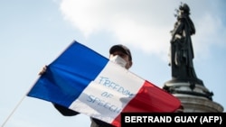 Мъж държи френски флаг с надпис "Свобода на словото" по време на масова демонстрация в памет на убития учител Самюел Пати. Париж, 18 октомври 2020 г.