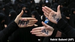 Hard-line Iranian protesters show their hands with writing in Persian that reads, "No to FATF," to protest the passage of a bill which joins Iran to the "Combating the Financing of Terrorism" on October 7.