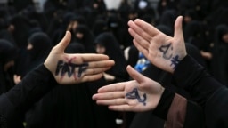Iranian hardliners protesting against FATF measures. The writings on their palms say "NO TO FATF'.