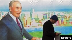 Қазақстан президенті Нұрсұлтан Назарбаевтың суреті бар баннер жанынан өтіп бара жатқан адам. Алматы, 28 қараша 2012 жыл.
