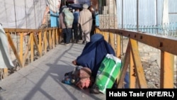 A woman and child beg on a bridge in Ghazni.