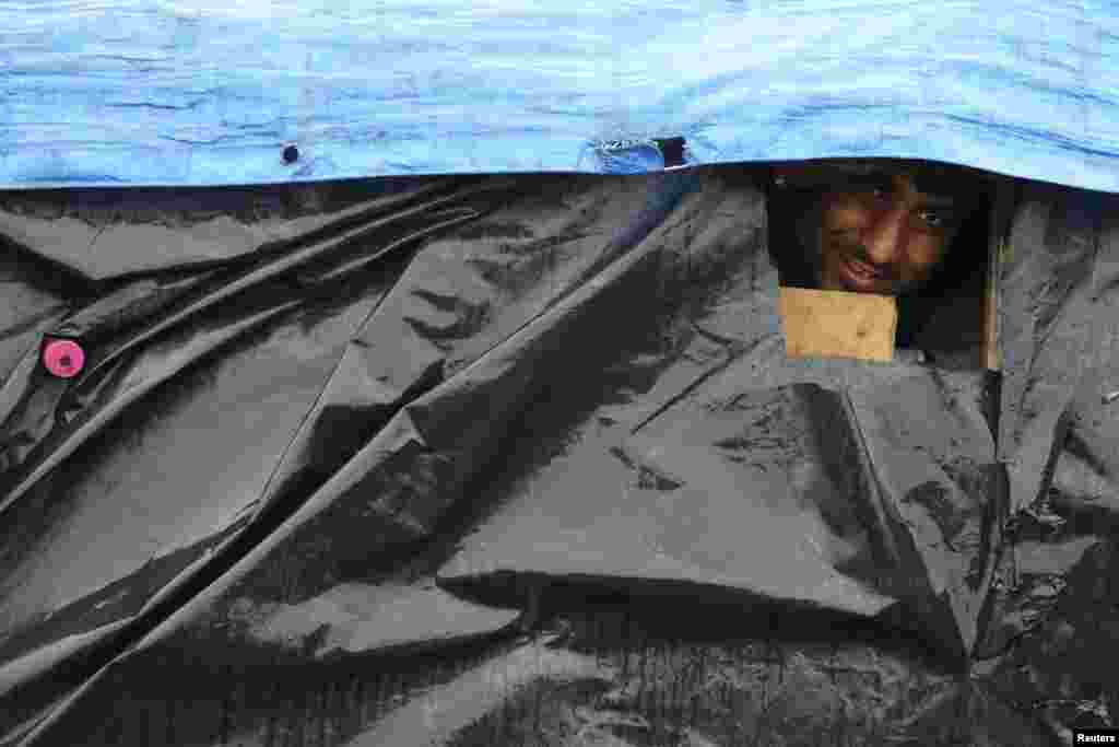 An Afghan migrant looks out the window of his makeshift shelter at the harbour in Calais, France. (Reuters/Pascal Rossignol)