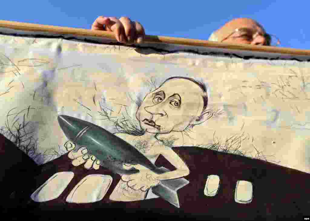 An opposition supporter holds a placard depicting Russian President Vladimir Putin during an opposition rally against the establishment of a Russian military base in Belarus, in Minsk, on October 4. (epa/Tatyana Zenkovich)