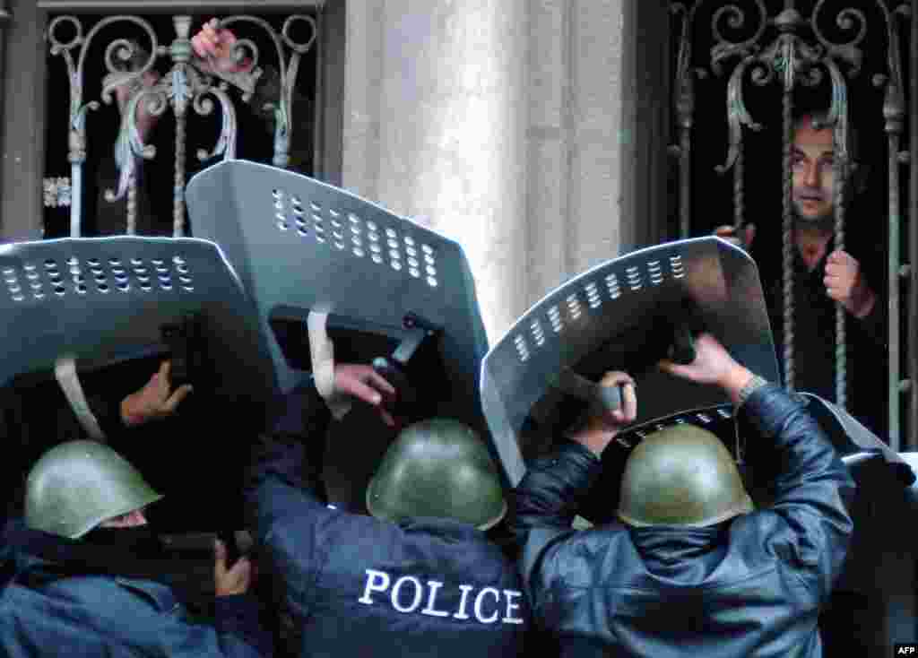 Georgian police guard the entrance of the parliament building in Tbilisi while opposition supporters storm it on November 22.