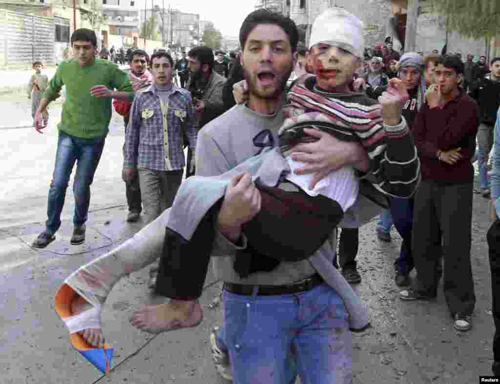 A man carries a child who was wounded after a missile hit the al-Myassar neighborhood of Aleppo, Syria. (Reuters/Muzaffar Salman)