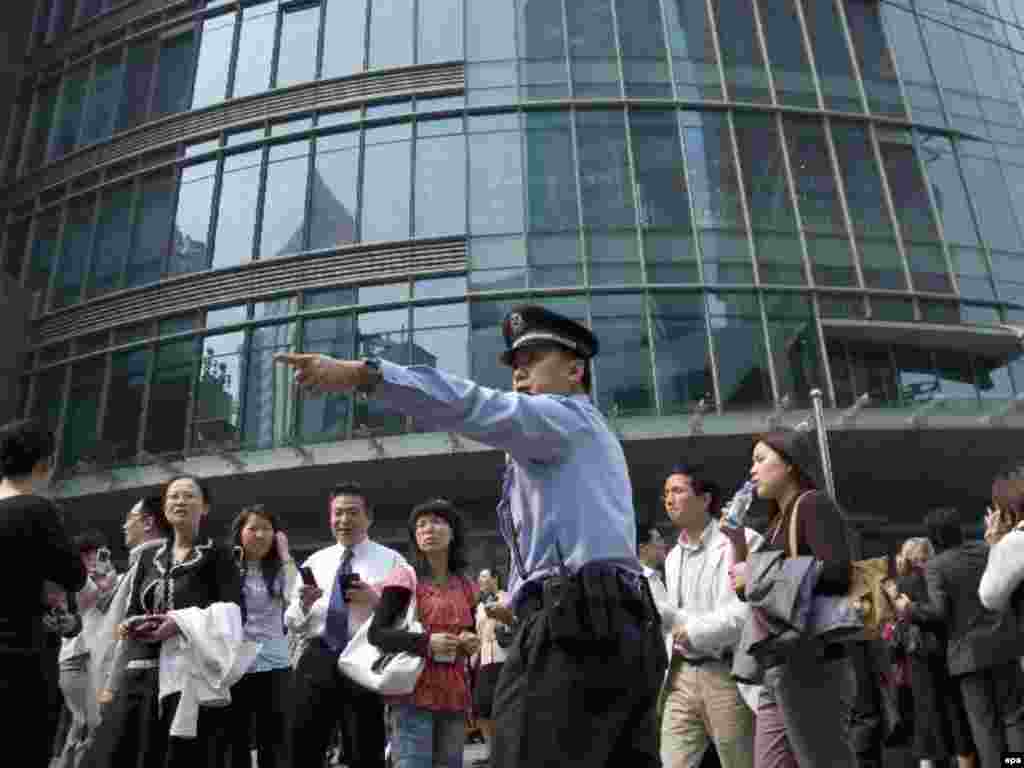 Полицейский показывает пути эвакуации, Шанхай, 12 мая 2008