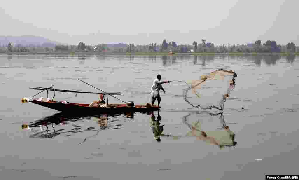A Kashmiri boatman throws his net to catch fish from the waters of Dal Lake in Srinagar, India. (epa-EFE/Farooq Khan)