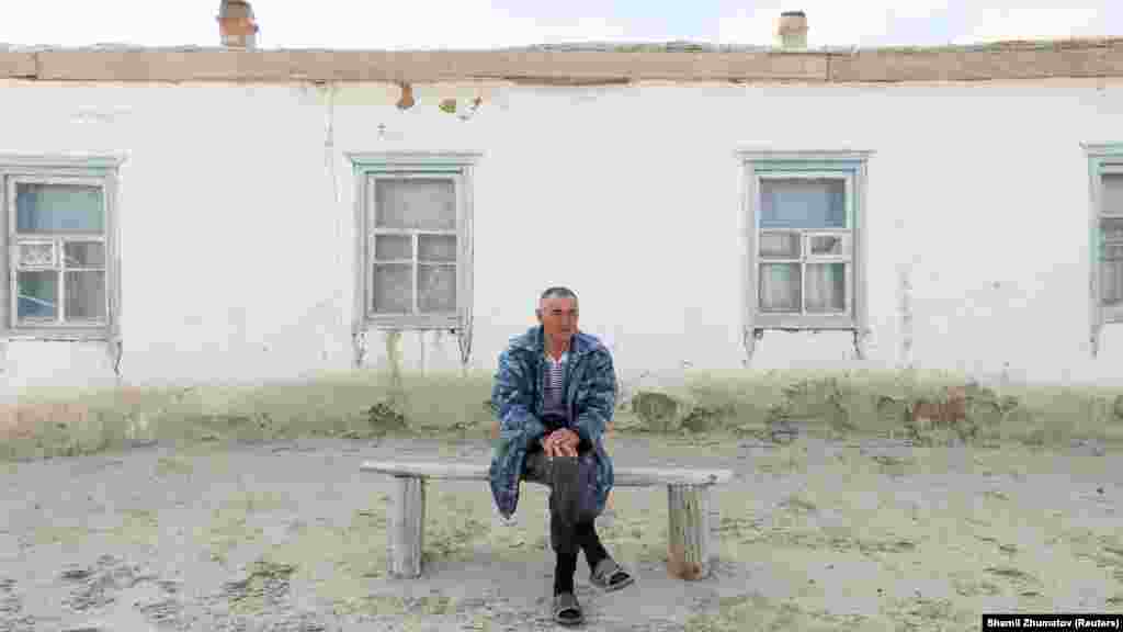 Ералы Серимбетов, родившийся в 1961 году, сидит перед своим домом, окруженным дюнами в отдаленной части села Каратерен.