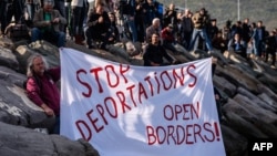 German activists show a banner during the arrival of a small Turkish ferry carrying migrants in Dikili on April 4.