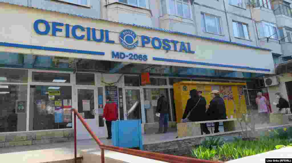 În fața unui oficiu poștal din Chișinău oamenii stau la rând păstrând distanța de minim un metru, așa cum recomandă și un afiș postat pe ușă. Intră doar un număr limitat de persoane, iar la intrare e obligatorie dezinfectarea mâinilor. 