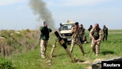 Kurdish peshmerga fighters fire a mortar during clashes with Islamic State (IS) militants near the town of Dokuk in Iraq's Kirkuk province, on March 18.