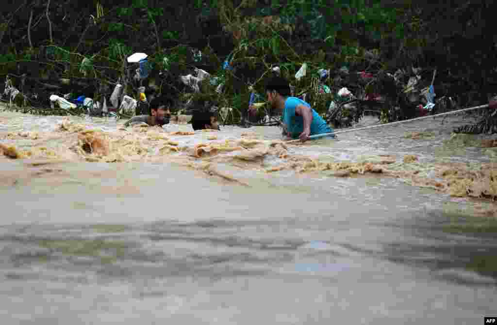 Pakistani residents hold onto a rope as they evacuate a flooded area in Karachi.