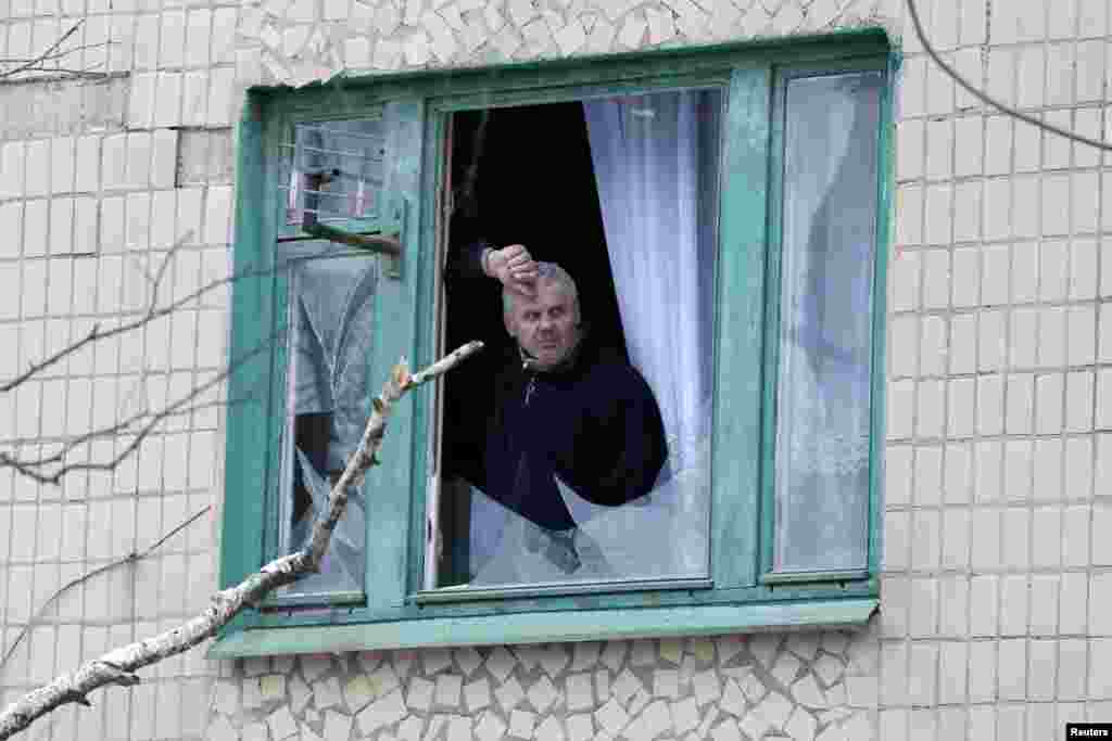 Житель Краматорска выглядывает из окна, разбитого в результате обстрела города 10 февраля.