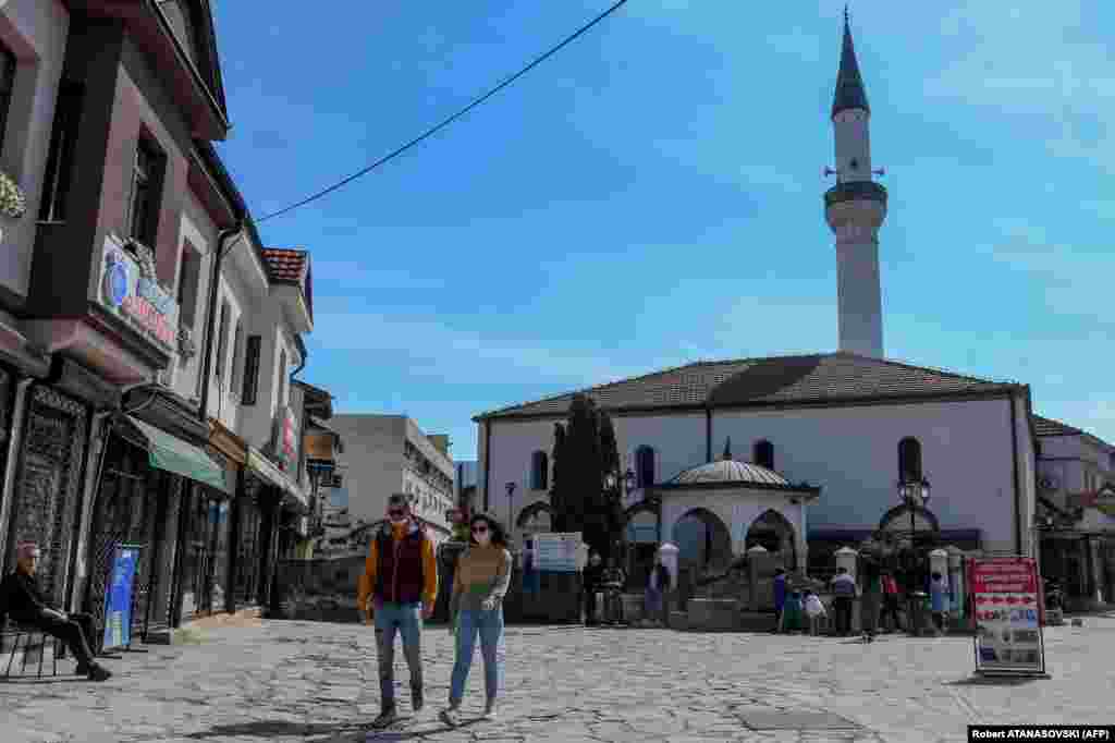 Луѓе со заштитни маски шетаат пред Мурат Пашината џамија во Скопје на 23 април. Исламската верска заедница на Северна Македонија донесе одлука да ги затвори сите џамии за време на Рамазан за да се спречи ширењето на коронавирусот.