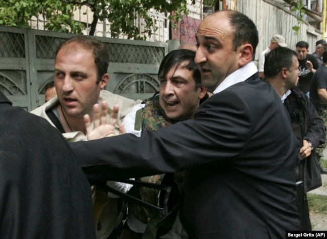 Охранники уводят президента Михаила Саакашвили (в центре) в укрытие после того, как была объявлена воздушная тревога. Гори, 11 августа 2008 года (период "пятидневной войны")