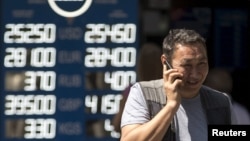 Чоловік говорить по мобільному телефону біля курсу обміну валют. Алмати, 20 серпня 2015 року