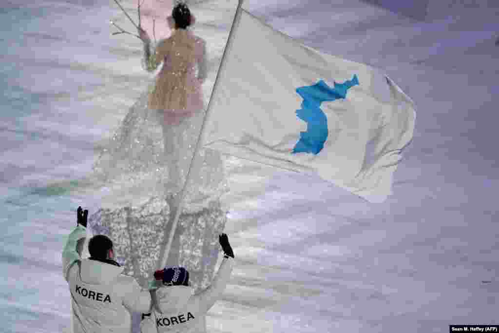 North and South Korean athletes entered the Olympic Stadium under a unified flag. It was carried by North Korean ice hockey player Hwang Chung Gum and South Korean bobsledder Won Yun-jong.