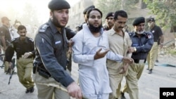 Pakistani police arrest a suspect after a suicide car-bomb attack outside a police station in Kohat on October 15.