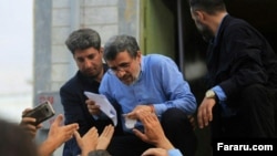Former president Mahmoud Ahmadinejad reading petitions by people during one his recent trips to regions. Undated