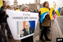 Сторонники евроинтеграции Украины держат плакат "Путин, руки прочь от Украины". Лондон, 15 декабря 2013 года.