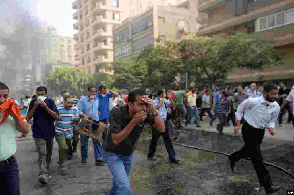 Supporters of the Muslim Brotherhood run for cover from tear gas near the Rabaa al-Adawiya protest camp.