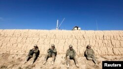 U.S. Army soldiers sit behind a wall as others search for explosives after an improvised explosive device damaged one of their armored vehicles during a road clearance patrol in Logar Province, in eastern Afghanistan. (file photo)