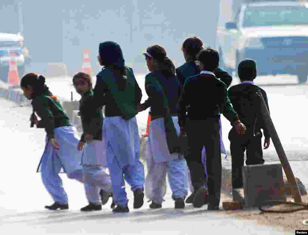 Pakistan -- Schoolchildren cross a road as they move away from a military run school that is under attack by Taliban gunmen in Peshawar, December 16, 2014