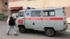 Belarus - April 10. 2020, a town of Dokšycy (Dokshytsy), Viciebskaja voblasc, a patient wearing mask is passing by the local hospital and an emergency car
