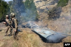 Pakistani soldiers stand next to what Pakistan says is the wreckage of an Indian fighter jet shot down in Pakistan-controlled Kashmir on February 27.