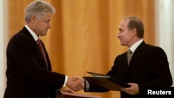 Russian President Vladimir Putin (right) and U.S. President Bill Clinton exchange agreements on the safe disposition of 68 metric tons of weapons-grade plutonium in Moscow on June 4, 2000.