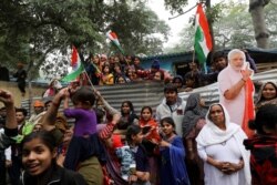 Hindu refugees from Pakistan's Sindh Province stand next to a cutout of Narendra Modi, India's Prime Minister, as they celebrate the Citizenship Amendment Bill being passed in India's Parliament.