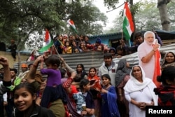 Hindu refugees from Pakistan's Sindh Province stand next to a cutout of Narendra Modi, India's Prime Minister, as they celebrate the Citizenship Amendment Bill being passed in India's Parliament.