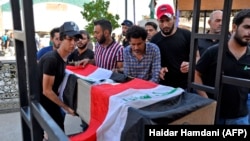 Mourners carry the Iraqi flag-draped coffin of a protester killed amid clashes during his funeral in the Najaf, October 4, 2019