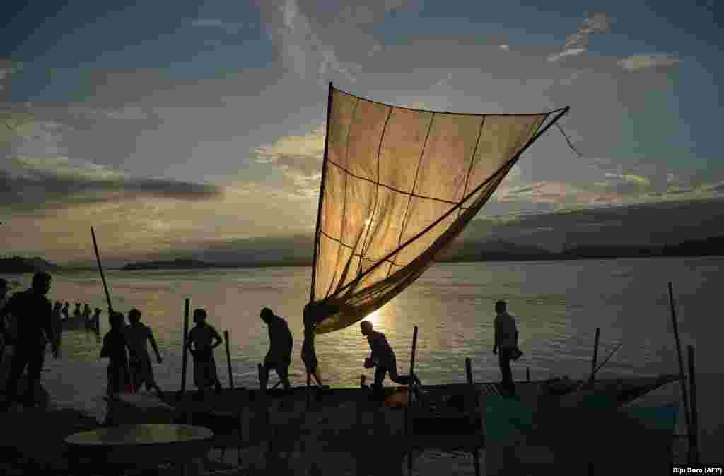 Indian fishermen load their boat with fish to sell at a market at the banks of the Brahmaputra River at Ujanbazar Ghat in Guwahati. (AFP/Biju BORO)