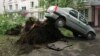 A car was lifted into the air by the roots of a large tree knocked down in the violent storm that shook Moscow on May 29.