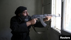 A Free Syrian Army fighter aims his AK-47 rifle through a window in Aleppo's Salaheddine neighborhood on April 28.