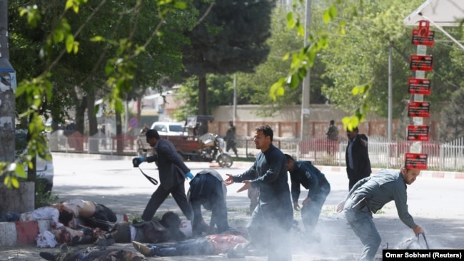 Афганские полицейские оказывают помощь раненным в результате взрыва журналистам. Кабул, апрель 2018 года