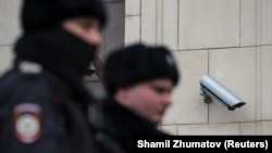  Ofițeri de poliție ruși care trec pe lângă o cameră de supraveghere în centrul Moscovei