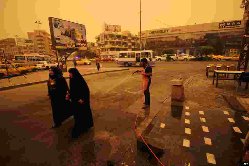 An Iraqi worker sprays water on the tarmac during a sandstorm in the capital Baghdad on September 1. (AFP/Haidar Mohammed)&nbsp;