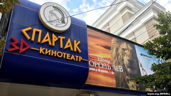 Фасад кинотеатра «Спартак», Симферополь, июль 2019 год. В фойе большинства кинотеатров располагаются фирменные стенды и афиши о кинофильмах, которые предоставляются дистрибьютером вместе с фильмокопией