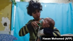 A Syrian boy holds an oxygen mask over the face of an infant at a makeshift hospital following a reported gas attack on the rebel-held besieged town of Douma on January 22.