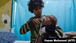 A Syrian boy holds an oxygen mask over the face of an infant after an alleged chlorine gas attack in eastern Ghouta in January.