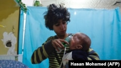 Maska na licu bebe nakon navodnog hemijskog napada u predgrađu Damaska